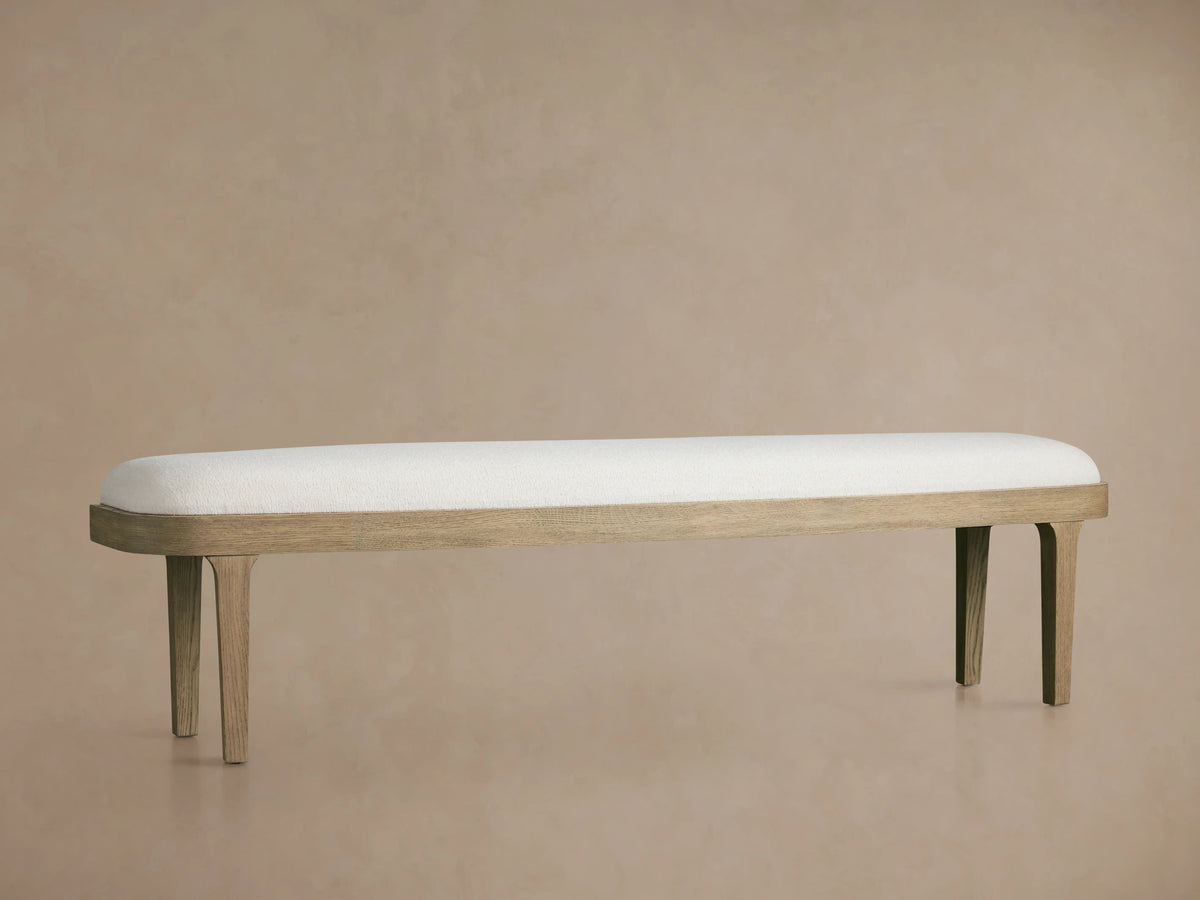 Danny Bench in oak wood with an off-white upholstered seat, supported by four slender legs, against a neutral background.