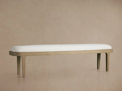 Danny Bench in oak wood with an off-white upholstered seat, supported by four slender legs, against a neutral background.