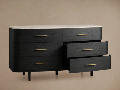 Danny Six-Drawer Dresser in ebony finish, features smooth, curved design with brass pulls and white marble top on wooden floor.