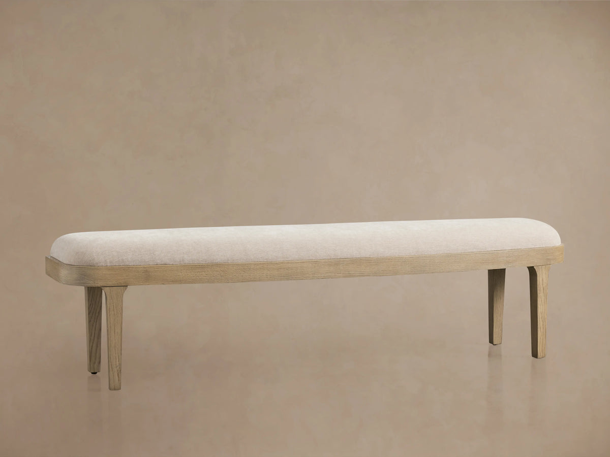 Danny Bench in oak wood with a fawn finish. Upholstered in light fabric with padded cushioning, featuring straight legs.