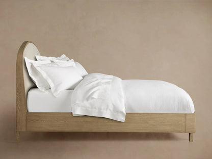 Rounded corner of Danny Bed's headboard, crafted from oak wood with beige fabric upholstery and visible wood grain texture.