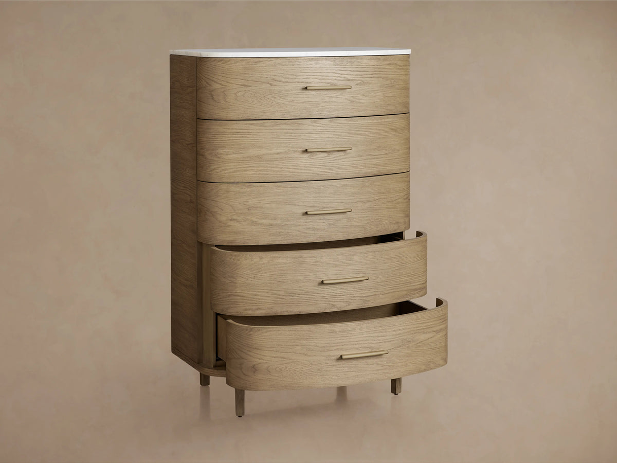 Danny Five-Drawer Dresser made of oak wood in a light fawn finish with brass pulls and a white marble top.