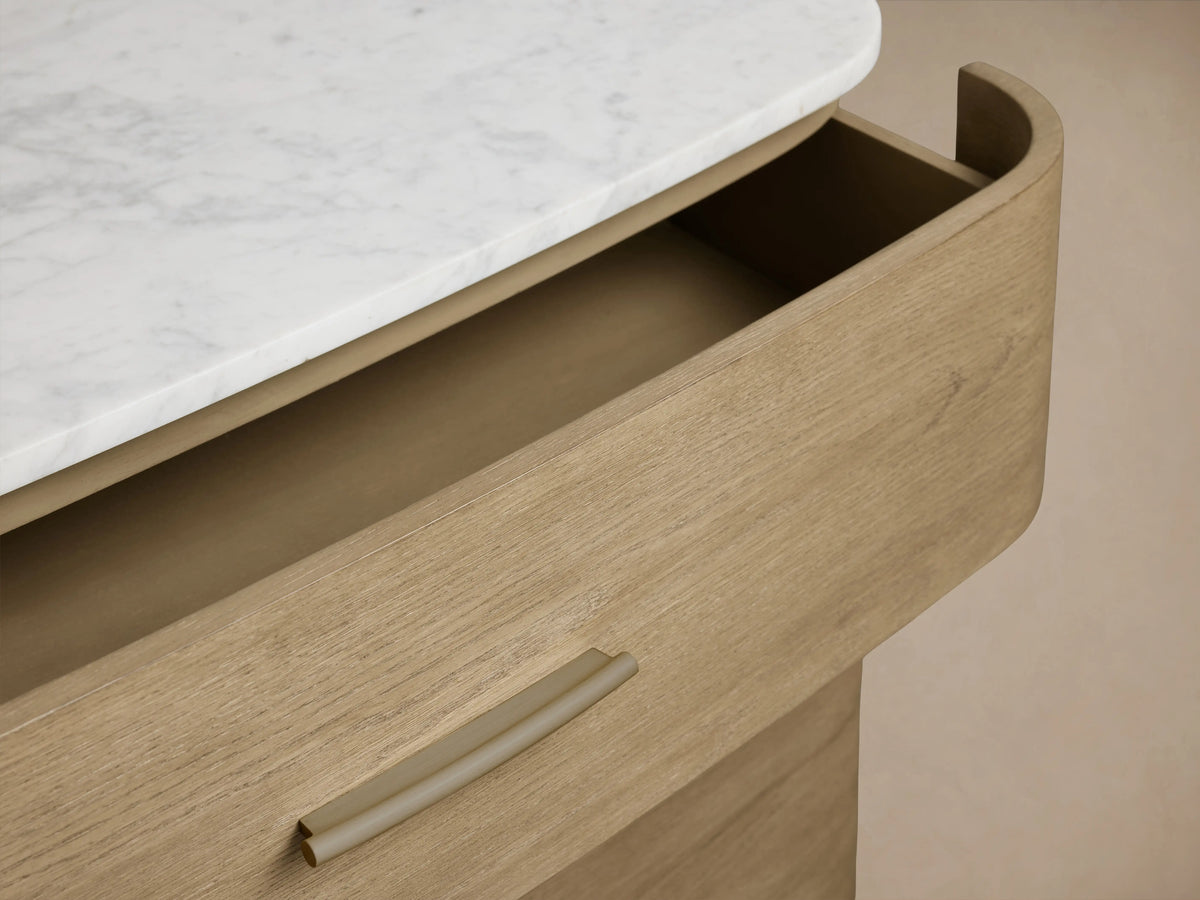 Danny Six-Drawer Dresser showing an open oak wood drawer with a brass pull, highlighted by a cream marble top with visible veining.