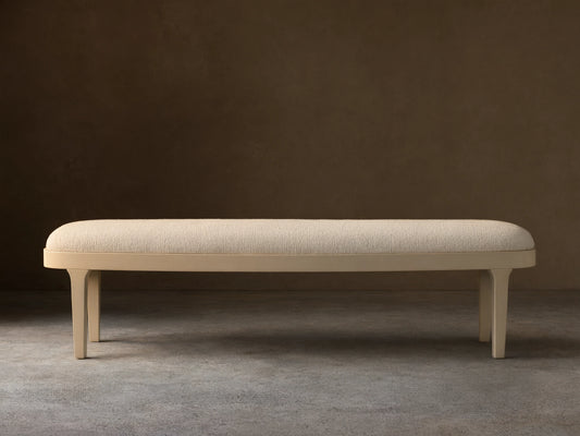 Danny Bench in Fumo. Off-white upholstered top with rounded edges and a sleek matching frame, seen frontally on a wood floor.