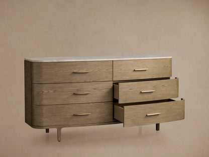 Danny Six-Drawer Dresser in oak with fawn finish, featuring a white marble top and brass pulls. Some drawers open, showcasing design.