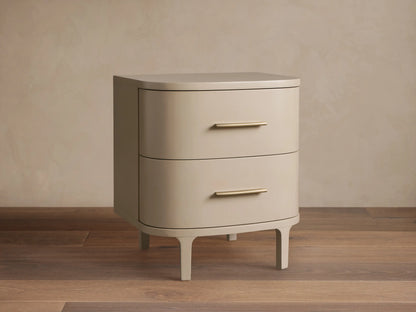 Danny Nightstand in fumo: light beige, rounded nightstand with two drawers, horizontal brass pulls, on short splayed legs.