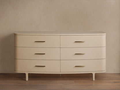 Danny Six-Drawer Dresser in Fumo. Light cream-colored dresser with six drawers, brass pulls, rounded edges, and tapered legs.