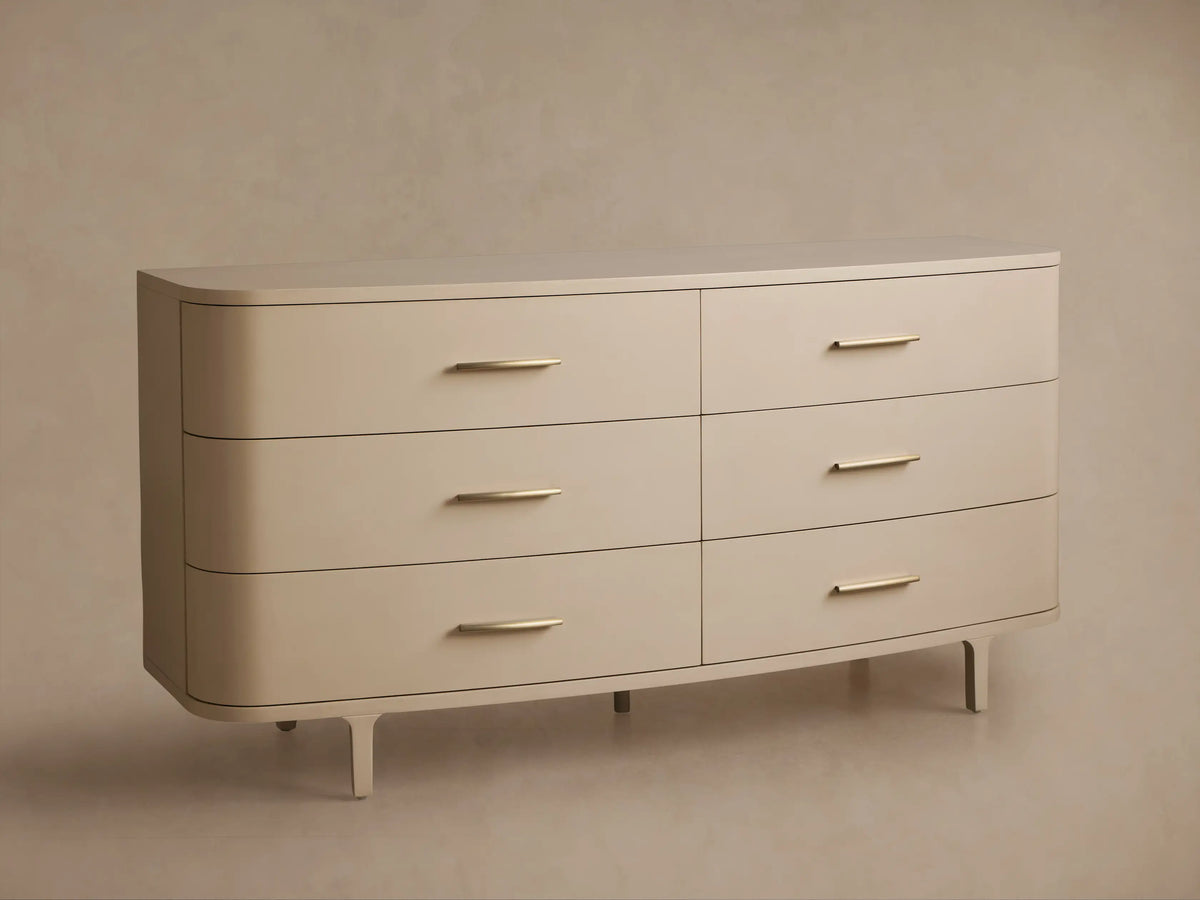 Danny Six-Drawer Dresser in Fumo. Light cream-colored dresser with six drawers, brass pulls, rounded edges, and tapered legs.