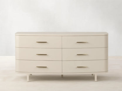 Danny Six-Drawer Dresser in Fumo. Light cream-colored dresser with six drawers, brass pulls, rounded edges, and tapered legs.
