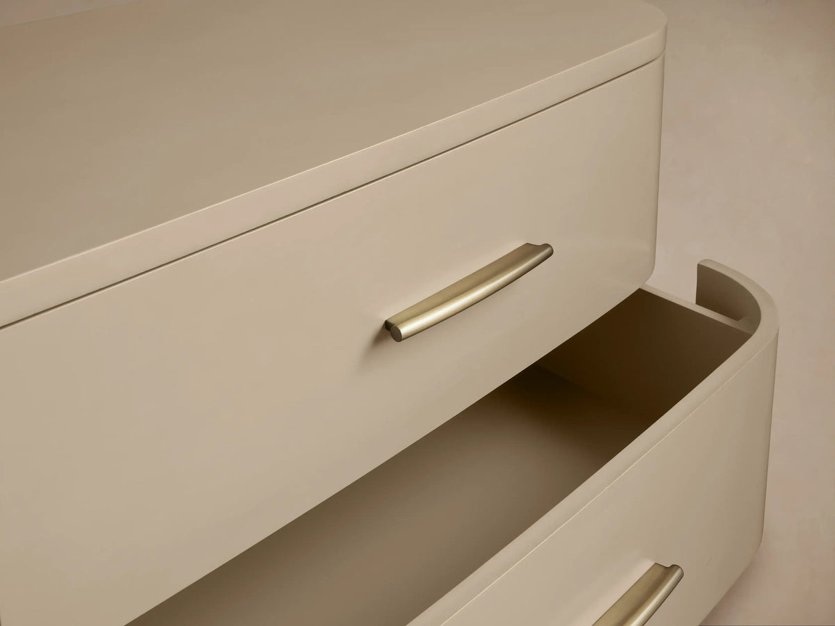 Danny Nine-Drawer Dresser in Fumo. Light grey curved dresser with 9 drawers and brass pulls on tapered legs, front view.