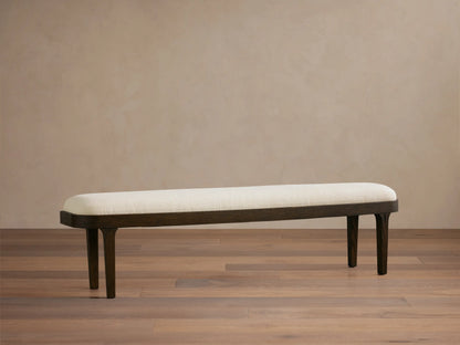 Danny Bench: Long, light cream upholstered top with dark oak wood frame and legs, positioned straight-on in a room.