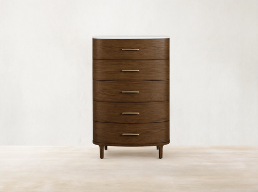 Danny Five-Drawer Dresser: Dark oak 5-drawer dresser with rounded front, brass pulls, white marble top. Standing on wooden floor.