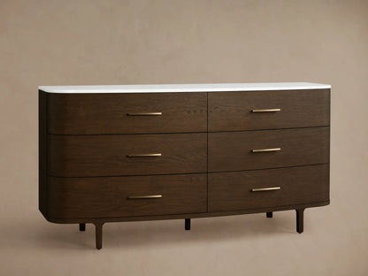 Full front view of a dark brown oak Danny Six-Drawer Dresser with a white marble top, brass pulls, and curved edges.