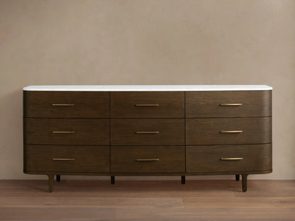 Danny Nine-Drawer Dresser: Dark oak wood with rounded edges, white marble top, nine brass-pull drawers, and tapered legs.