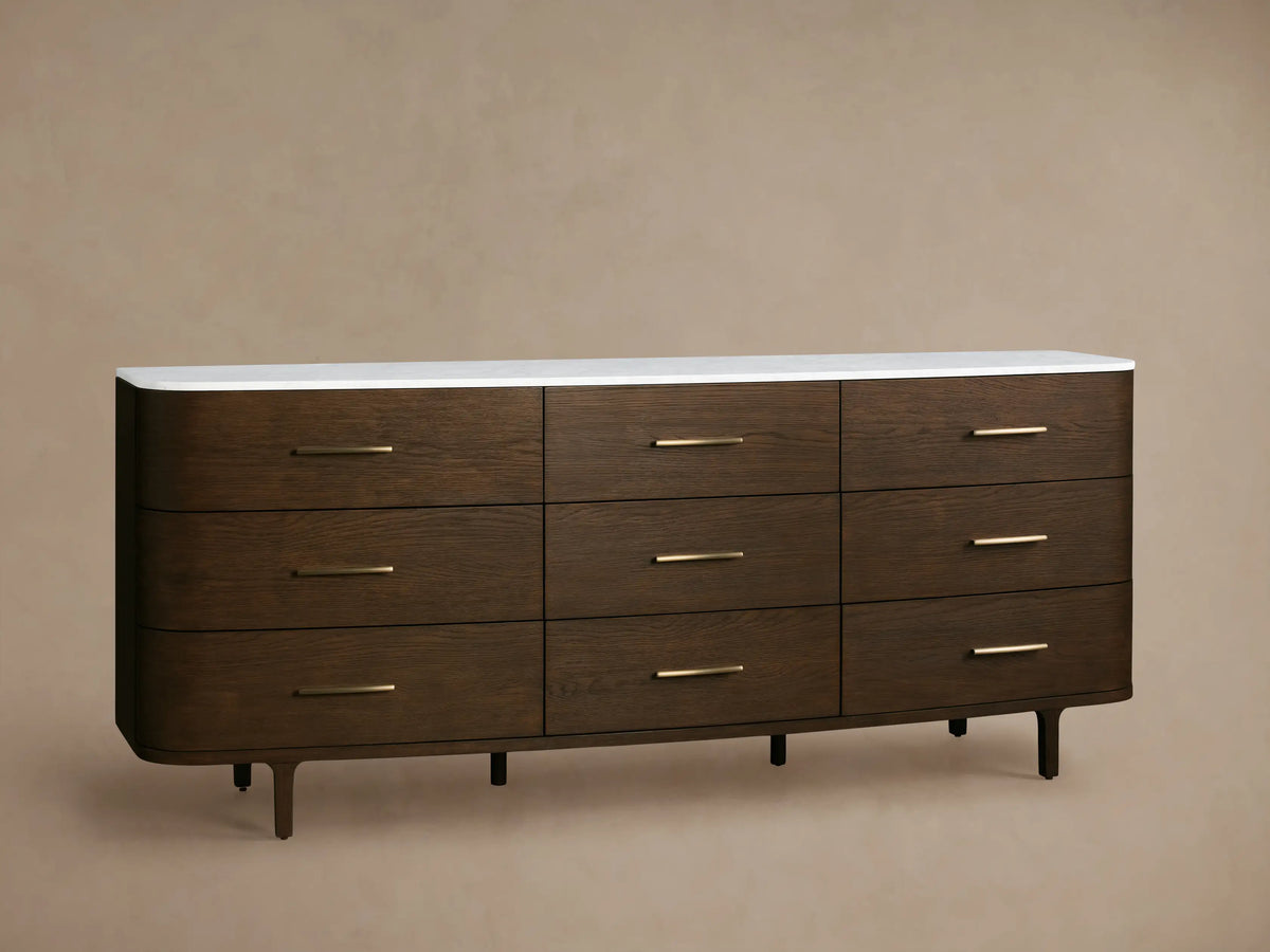 Danny Nine-Drawer Dresser: Dark oak wood with rounded edges, white marble top, nine brass-pull drawers, and tapered legs.