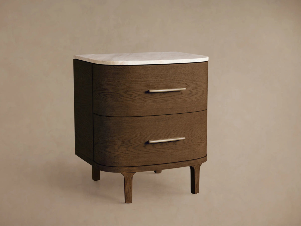 Danny Nightstand: Dark oak wood, two rounded drawers with brass pulls, white marble top, on a wood floor against a light wall.