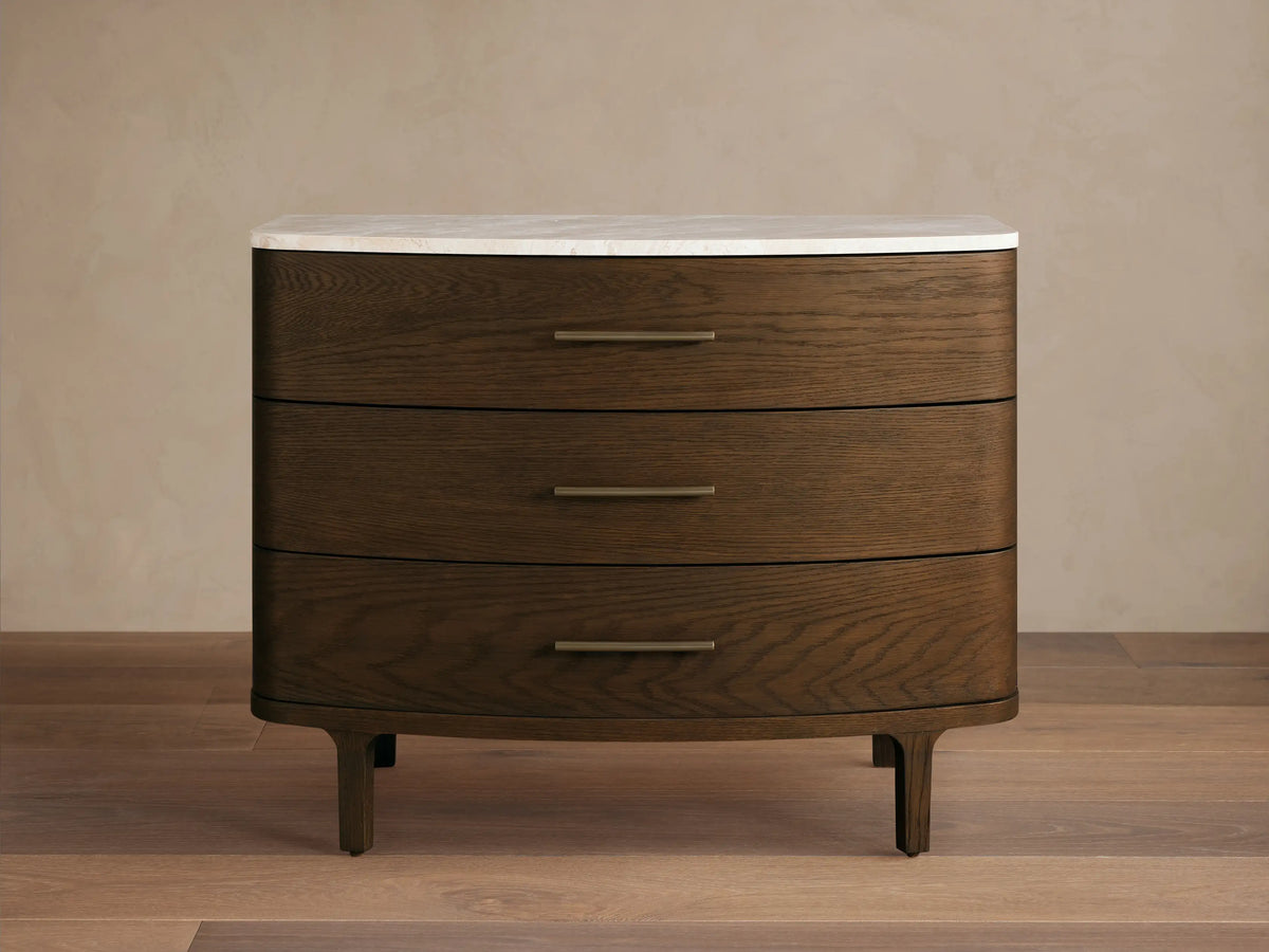 Danny Three-Drawer Chest: dark brown oak with rounded edges, white marble top, three horizontal brass handles, on wood floor.