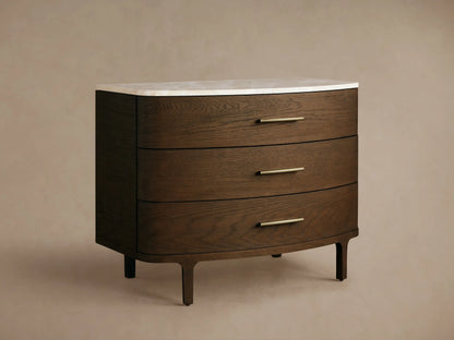 Danny Three-Drawer Chest: dark brown oak with rounded edges, white marble top, three horizontal brass handles, on wood floor.