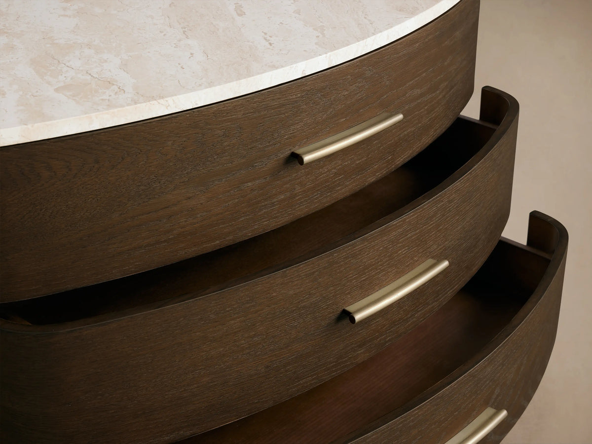 Danny Three-Drawer Chest: dark oak wood with curved front, white marble top, three drawers with brass bar pulls, and tapered legs.