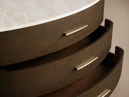 Danny Three-Drawer Chest: dark oak wood with curved front, white marble top, three drawers with brass bar pulls, and tapered legs.