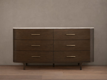 Danny Six-Drawer Dresser, dark oak with curved edges, white marble top, six drawers, brass pulls, on wooden floor.