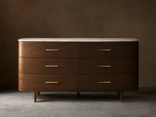 Danny Six-Drawer Dresser, dark oak with curved edges, white marble top, six drawers, brass pulls, on wooden floor.