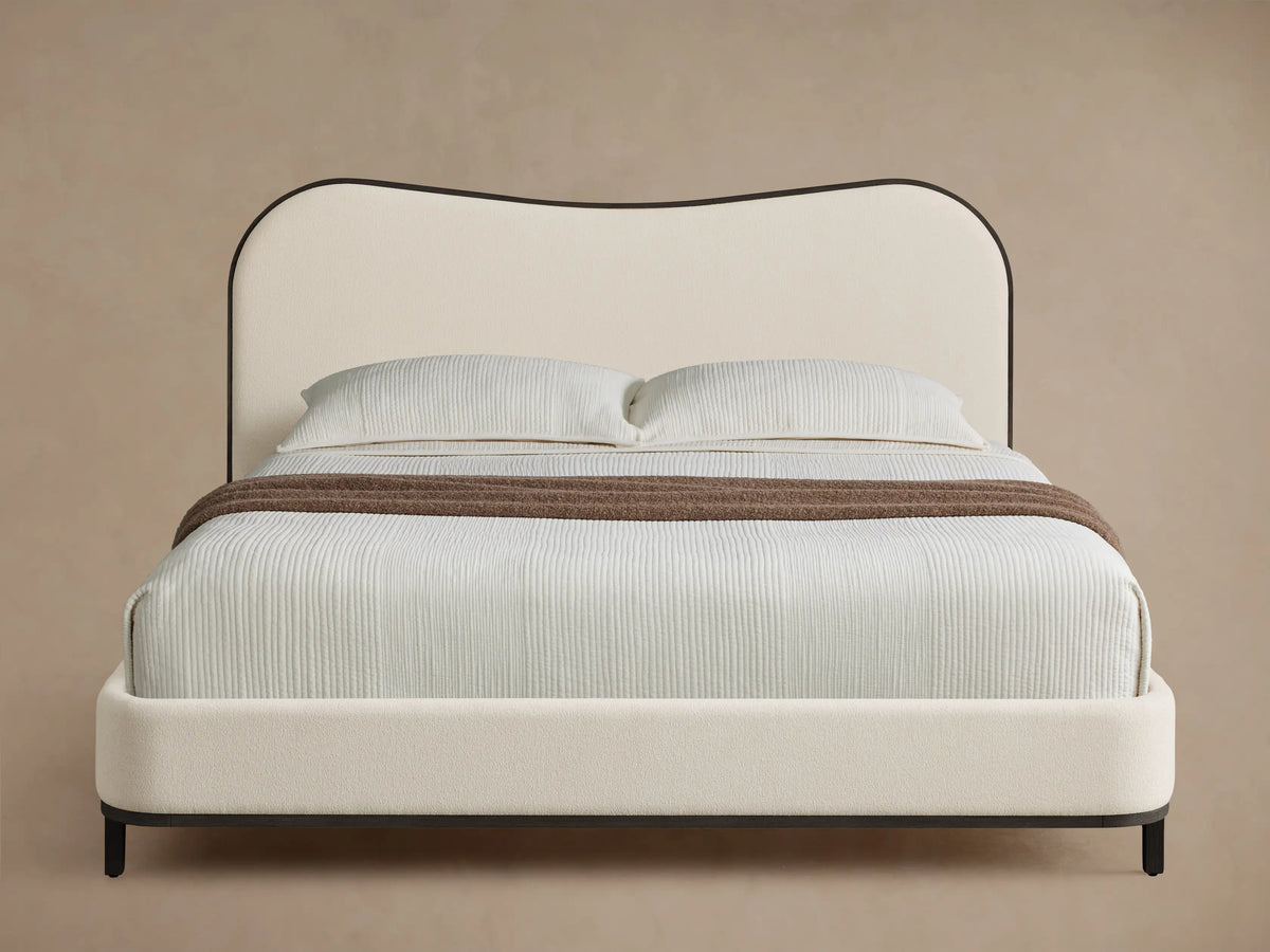 Front view of the Danny Camelback Bed™ with a beige and brown botanical pattern headboard and light taupe upholstered frame.