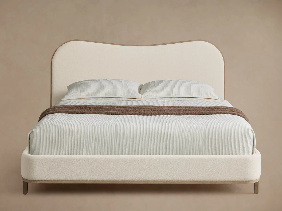 Front view of the Danny Camelback Bed, featuring a brown patterned camelback headboard and beige upholstered frame.