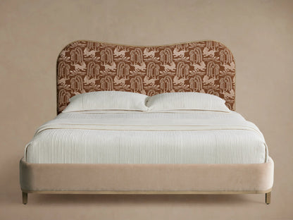 Danny Camelback Bed with a brown patterned camelback headboard, beige upholstered frame, and crisp white bedding.