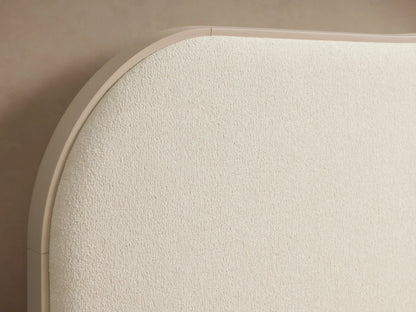 Danny Camelback Bed in light cream 'Fumo' fabric, with a camelback headboard, upholstered frame, and light ribbed bedding.