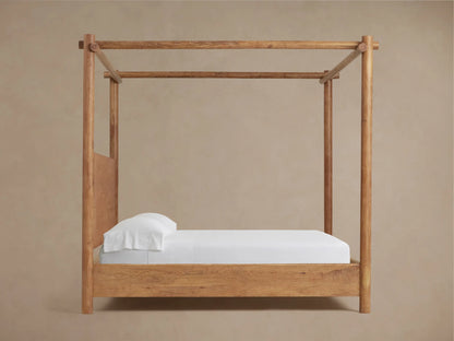 Close-up of Dutton Canopy Bed's acacia wood headboard with Vintage Teak finish, showing rich wood grain next to a rounded canopy post.