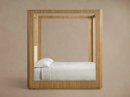 Close-up of the Finnley Canopy Bed with a light oak wooden frame, cream textured fabric, and a fluted side panel.