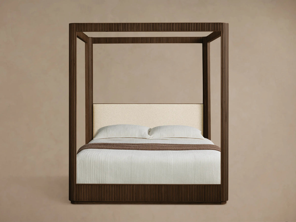 Front view of a dark brown Finnley Canopy Bed with reeding detail and an upholstered cream headboard, styled with white bedding.