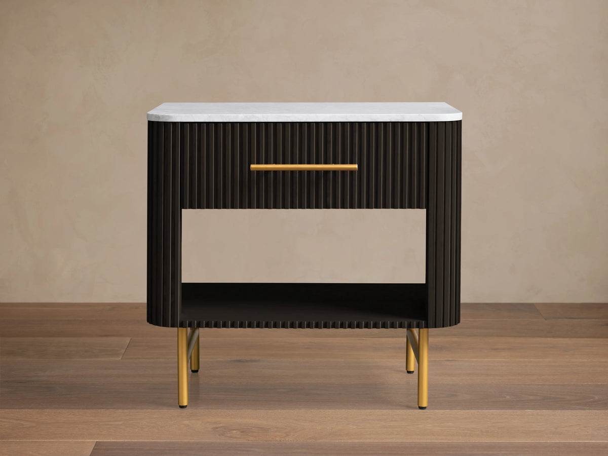 Finnley Open Nightstand with a marble top, brass-finished handle, dark ribbed body, open shelf, and brass legs on a wooden floor.