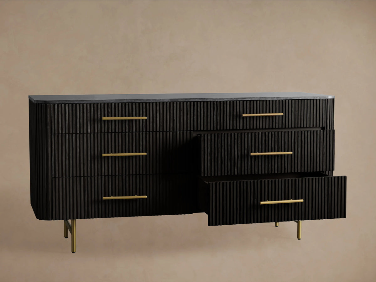 Finnley Six-Drawer Dresser in dark finish with ribbed texture, six brass-finished handles, and sleek metal legs on a wood floor.