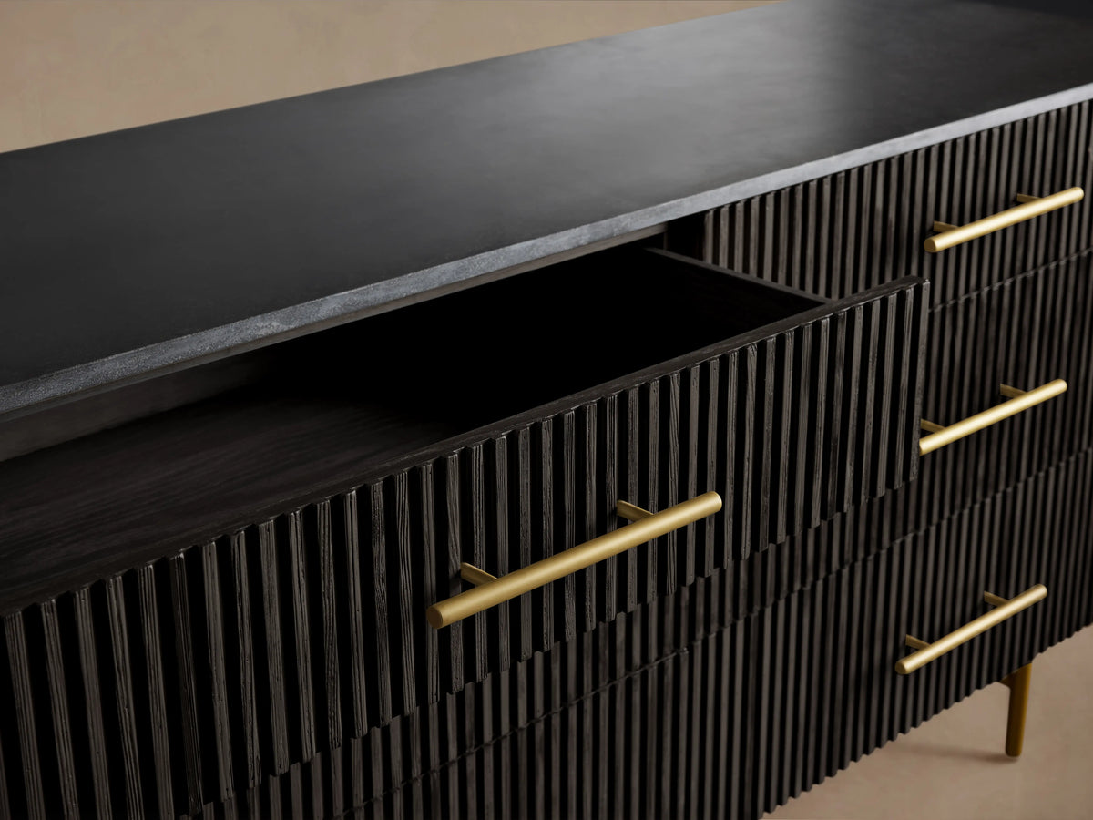 Finnley Six-Drawer Dresser with a dark finish, horizontal ribbed texture, brass handles, and partially open drawers on slender legs.