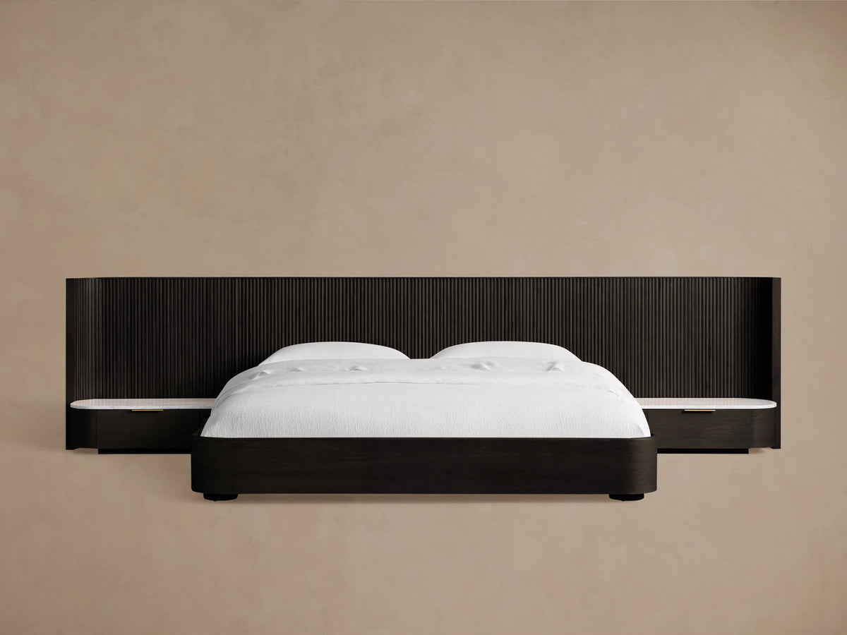 Finnley Extended Headboard Bed in dark wood finish, low-profile design, with white bedding, against a beige wall.