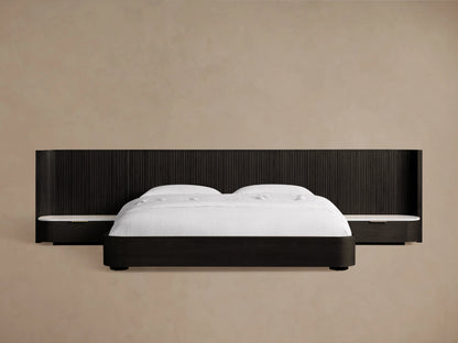 Finnley Extended Headboard Bed in dark wood finish, low-profile design, with white bedding, against a beige wall.
