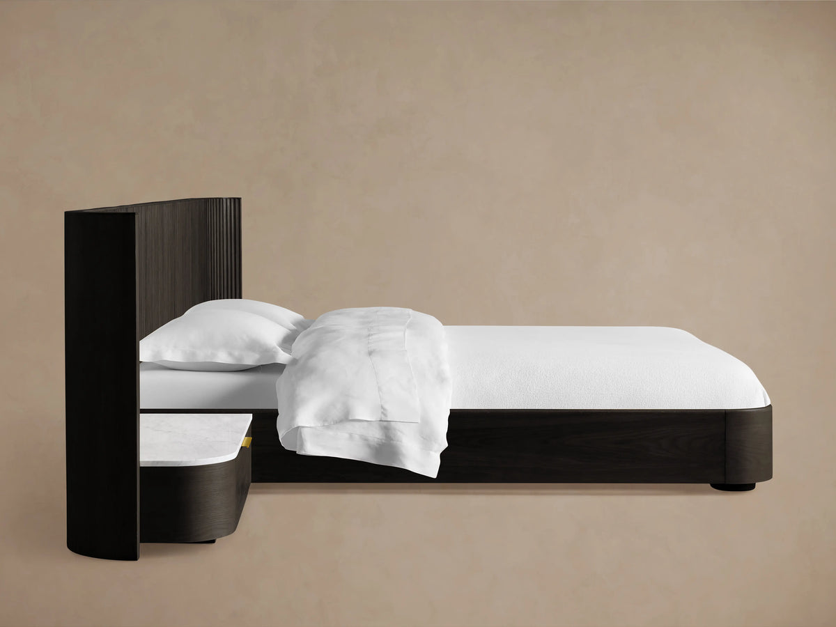 Top-down view of the Finnley Extended Headboard Bed showing a curved, grooved dark wood finish with a smooth white marble top and an open drawer with brass hardware.