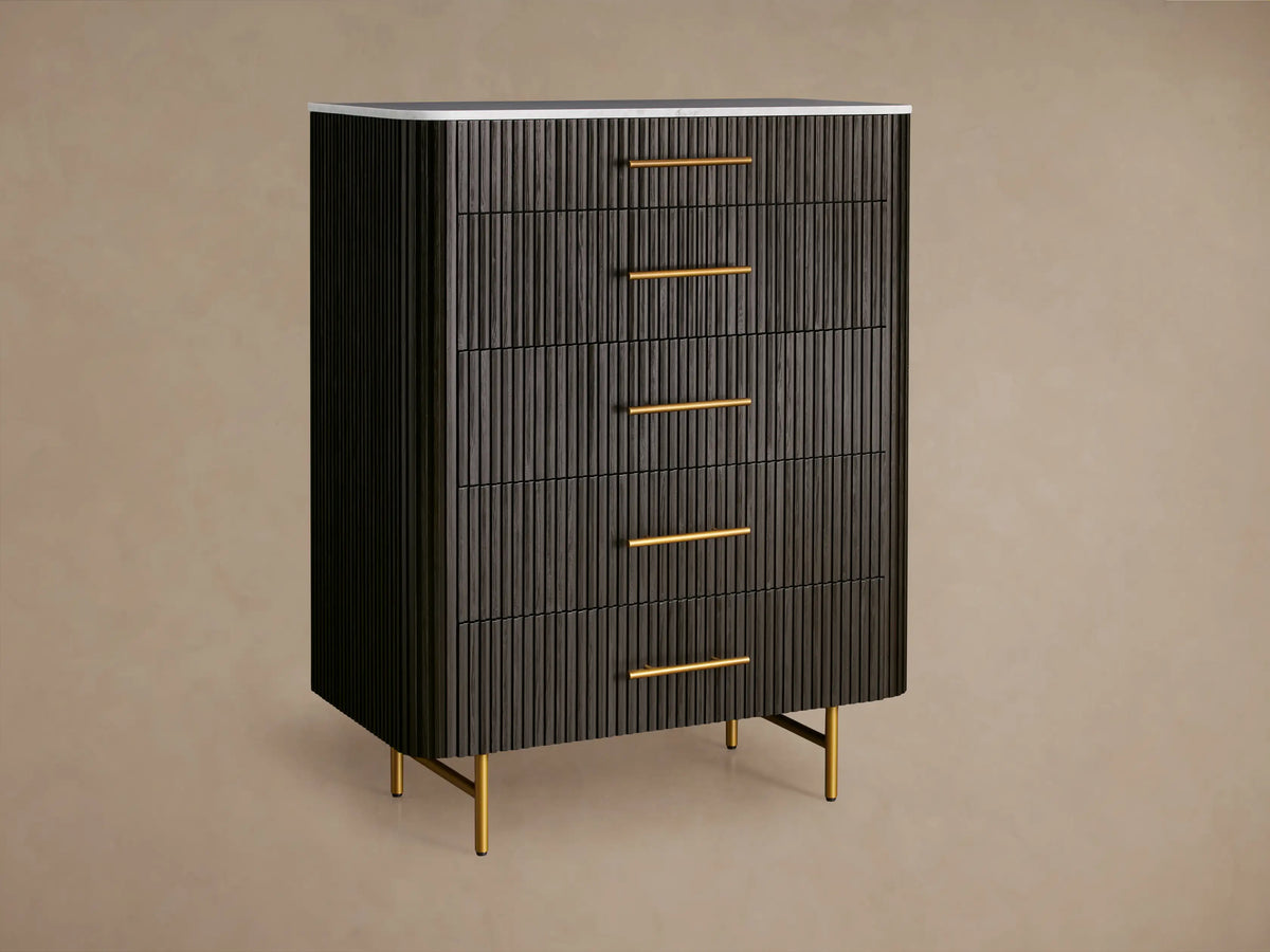 Finnley Five-Drawer Dresser, ebony finish with reeded drawers, white marble top, gold handles, and sleek gold legs.