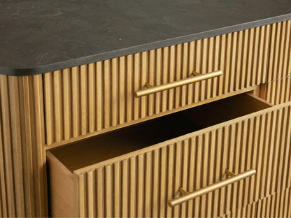 Finnley Nine-Drawer Dresser: Honey wood with vertical reeding, dark stone top, brass bar pulls, and legs. Two right drawers open.