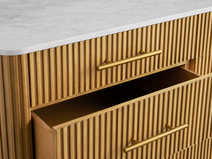 Finnley Nine-Drawer Dresser in honey wood with reeded front, white stone top, brass handles & legs. Two right drawers open.