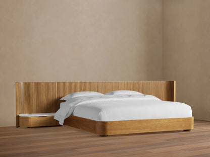Finnley Extended Headboard Bed in Honey finish with vertical reeded wood headboard, integrated nightstand with stone top, and white bedding.