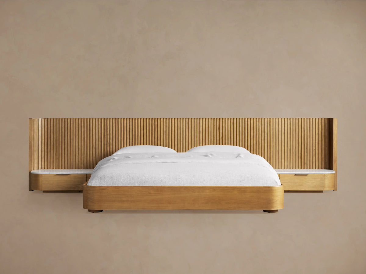 Finnley Extended Headboard Bed in Honey finish with vertical reeded wood headboard, integrated nightstand with stone top, and white bedding.