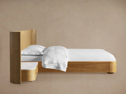 Finnley headboard detail: light wood with curved reeding, white marble top, and open drawer with brass handle.