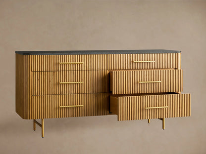 Finnley Six-Drawer Dresser, honey wood with vertical reeding detail, dark stone top, brass handles, on gold metal legs.