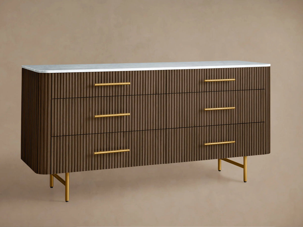 Finnley Six-Drawer Dresser: Mocha wood with vertical reeding, white stone top, six brass handles, and gold legs.
