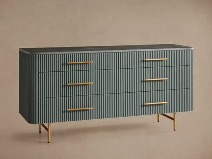 Finnley Six-Drawer Dresser with reeded dark gray-green drawers, brass pulls, a dark stone top, and slender brass legs.