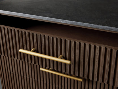 Close-up of Finnley Five-Drawer Dresser: dark brown reeded wood, two gold bar handles. Top drawer slightly open; black stone top.