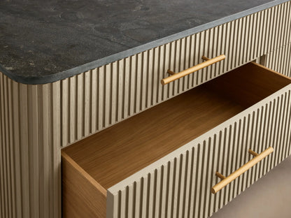 Finnley Six-Drawer Dresser with a light reeded body, dark stone top, six horizontal brass handles, and angled gold legs.